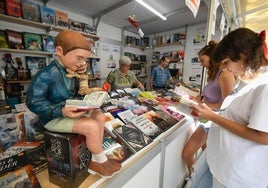 Dos lectoras ojean los libros de uno de los expositores de la Feria del Libro de Murcia, este viernes en el paseo Alfonso X.