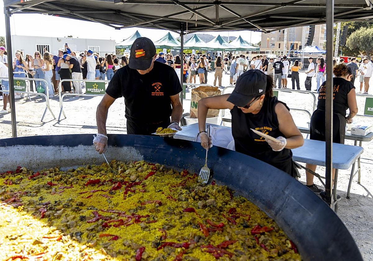 Dos cocineros sirven platos de arroz, en la explanada del campus de la Muralla del Mar.
