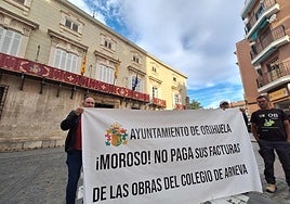 Lorenzo Espín (izquierda) sostiene una pancarta frente al Ayuntamiento de Orihuela.