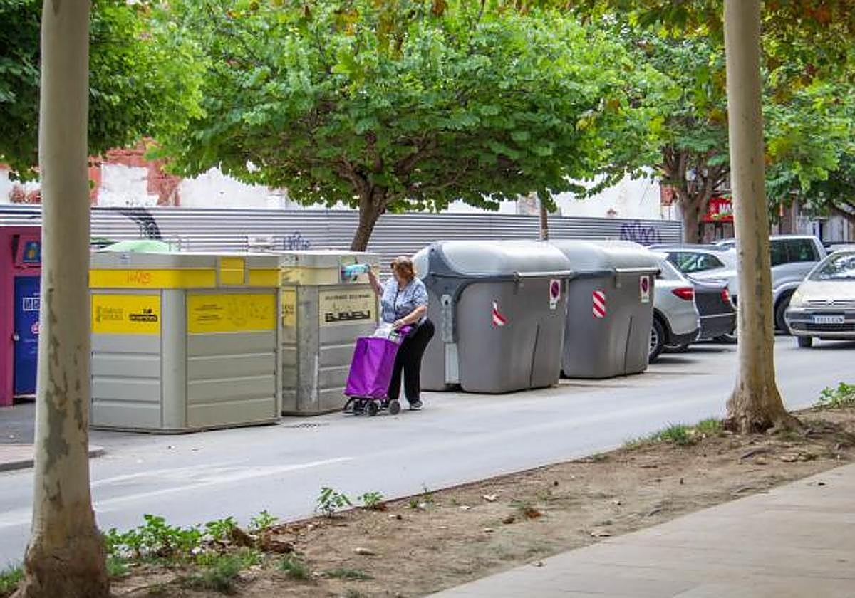 Una vecina deposita unas botellas de plástico en el contenedor amarillo en Los Andenes.