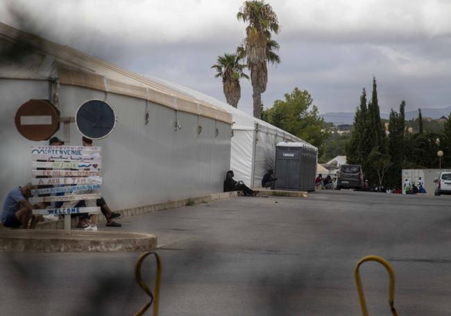 Inmigrantes sentados junto a las carpas instaladas en el patio.