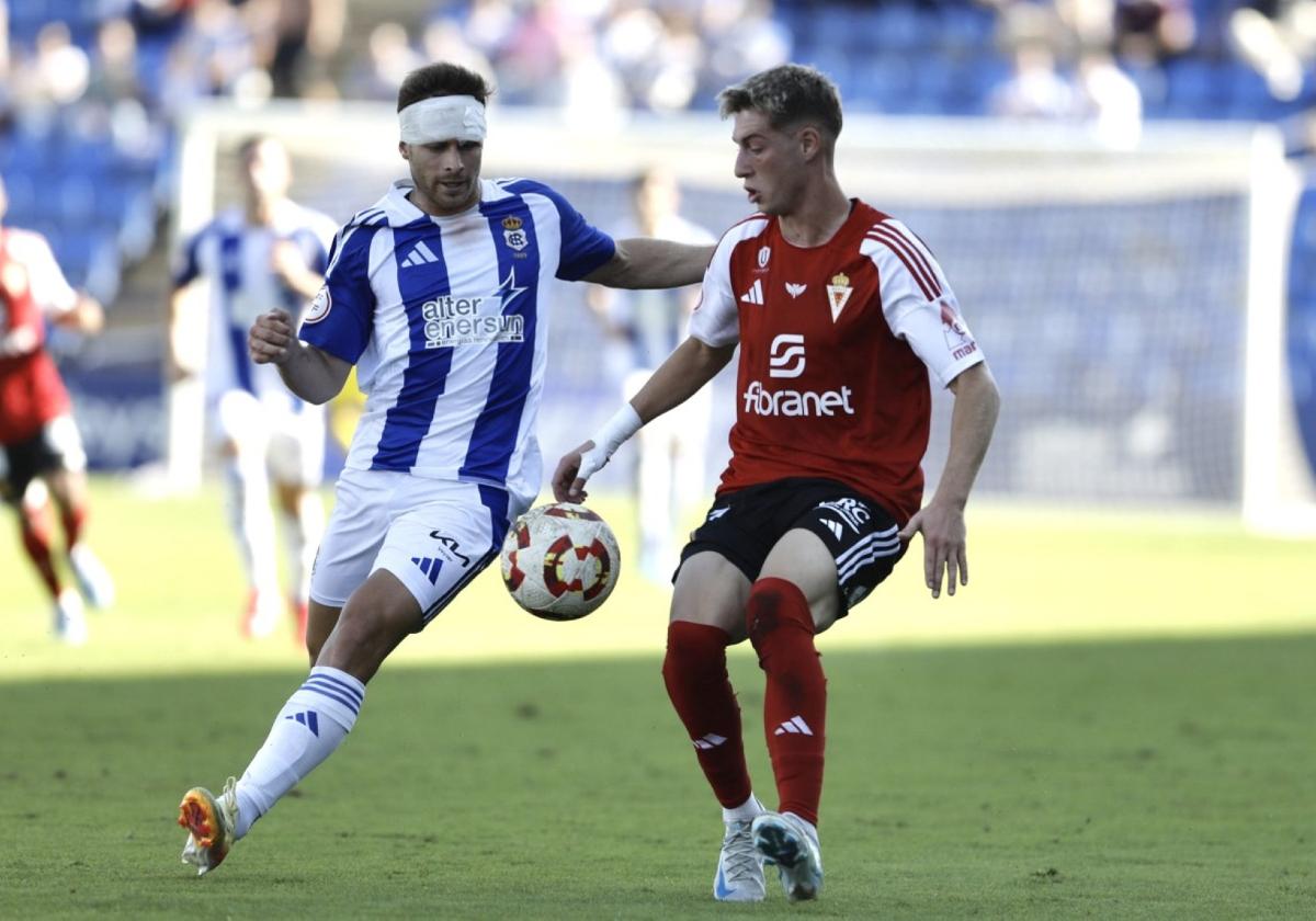 Antonio Toral, jugador del Real Murcia, juega un balón ante Dani Perejón, del Recreativo.