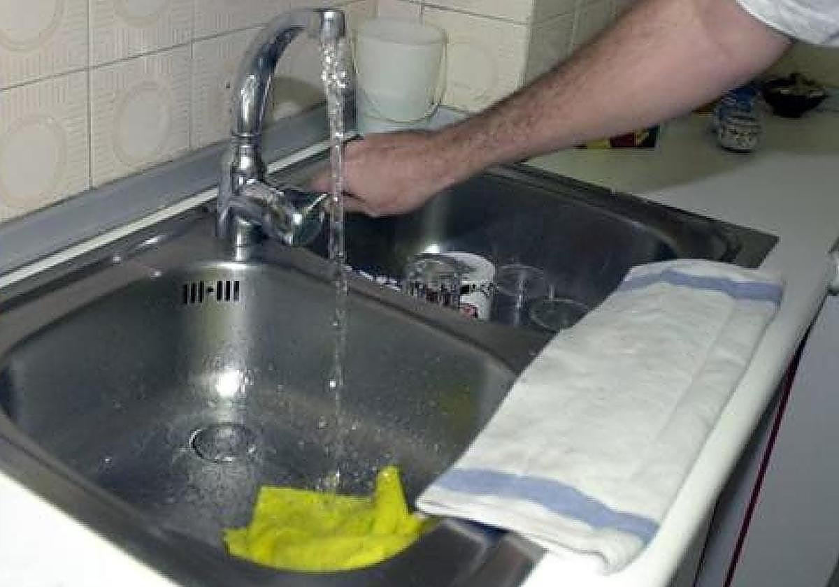 Una persona abre el grifo del fregadero de su cocina.