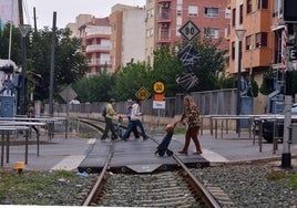 Vecinos de Alcantarilla cruzan el paso a nivel de la línea Cartagena-Chinchilla, que sigue dividiendo la ciudad en la calle Mayor.