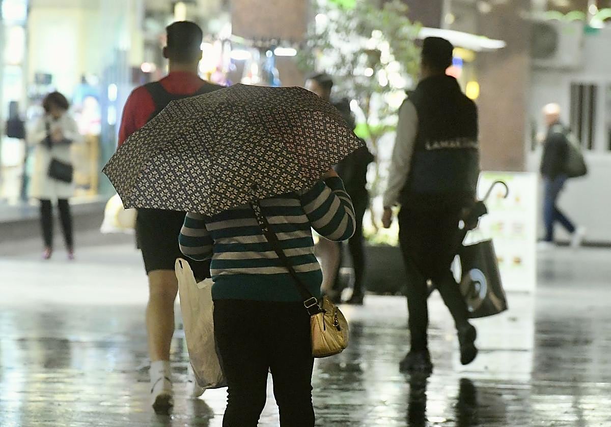 Peatones se protegen de la lluvia este lunes en Murcia.