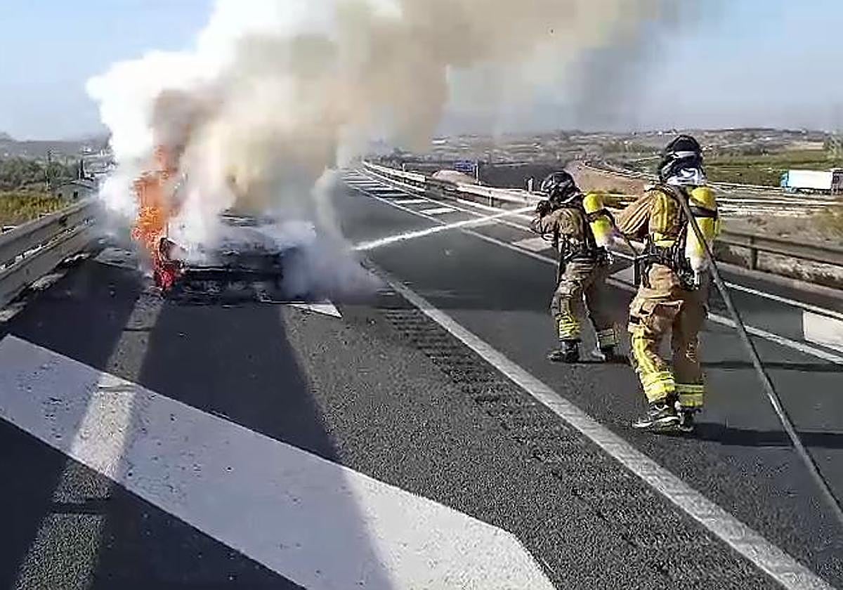 Dos bomberos sofocan el incendio en el vehículo.