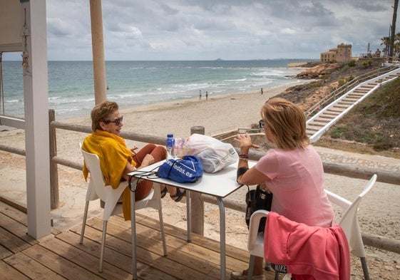 Dos mujeres toman un refresco en la terraza del chiringuito de la playa de los Jesuitas, en La Torre de la Horadada.