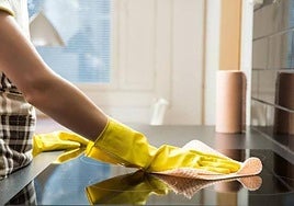 Una mujer limpia una cocina.