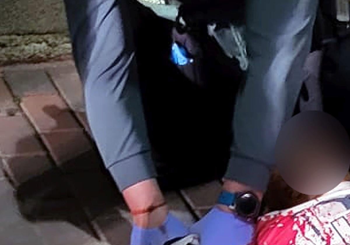 Un agente de la Guardia Civil le hace un torniquete en la muñeca al herido.