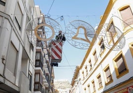 Colocación de las guirnaldas con motivos navideños en la calle Álamo.