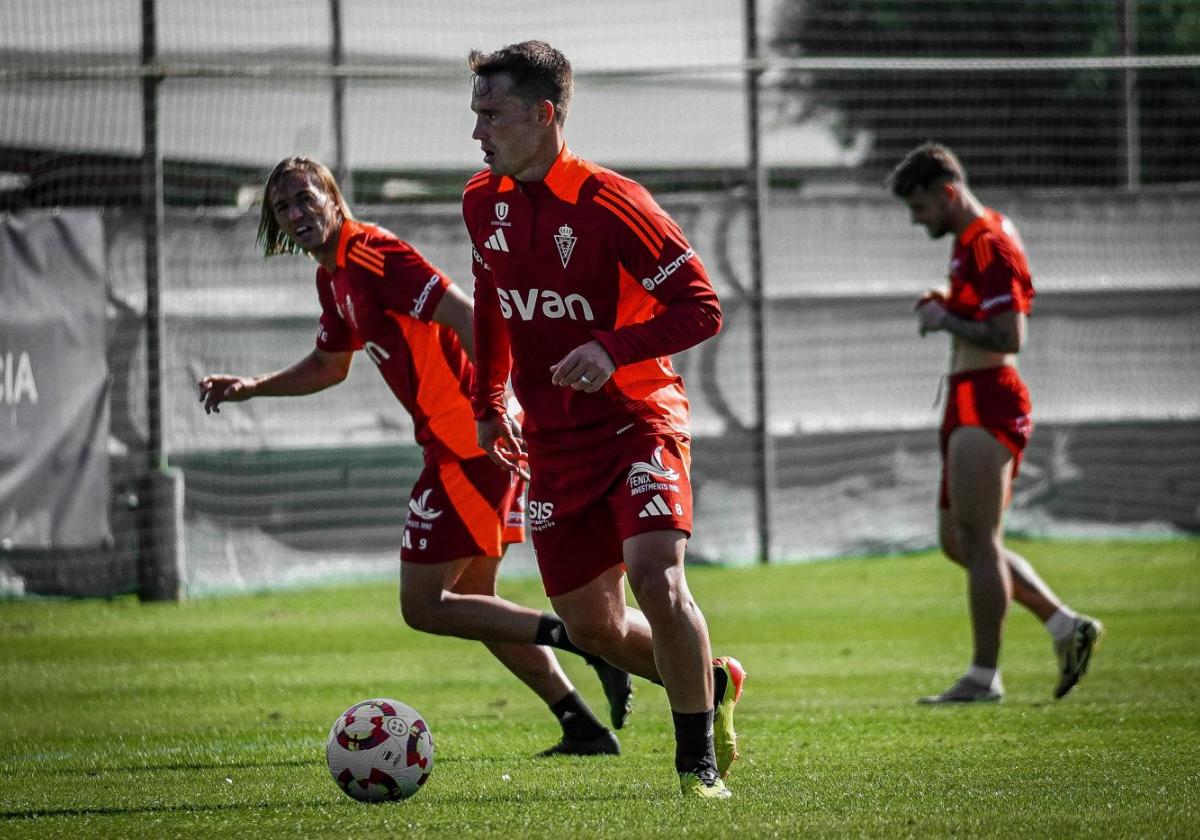 El centrocampista Pablo Larrea conduce un balón durante un entrenamiento del Real Murcia con Pedro Benito corriendo por detrás.