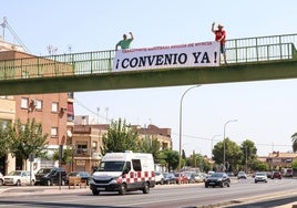 Dos trabajadores del transporte sanitario descuelgan una pancarta junto a La Arrixaca durante una jornada de huelga, el pasado mes de agosto.