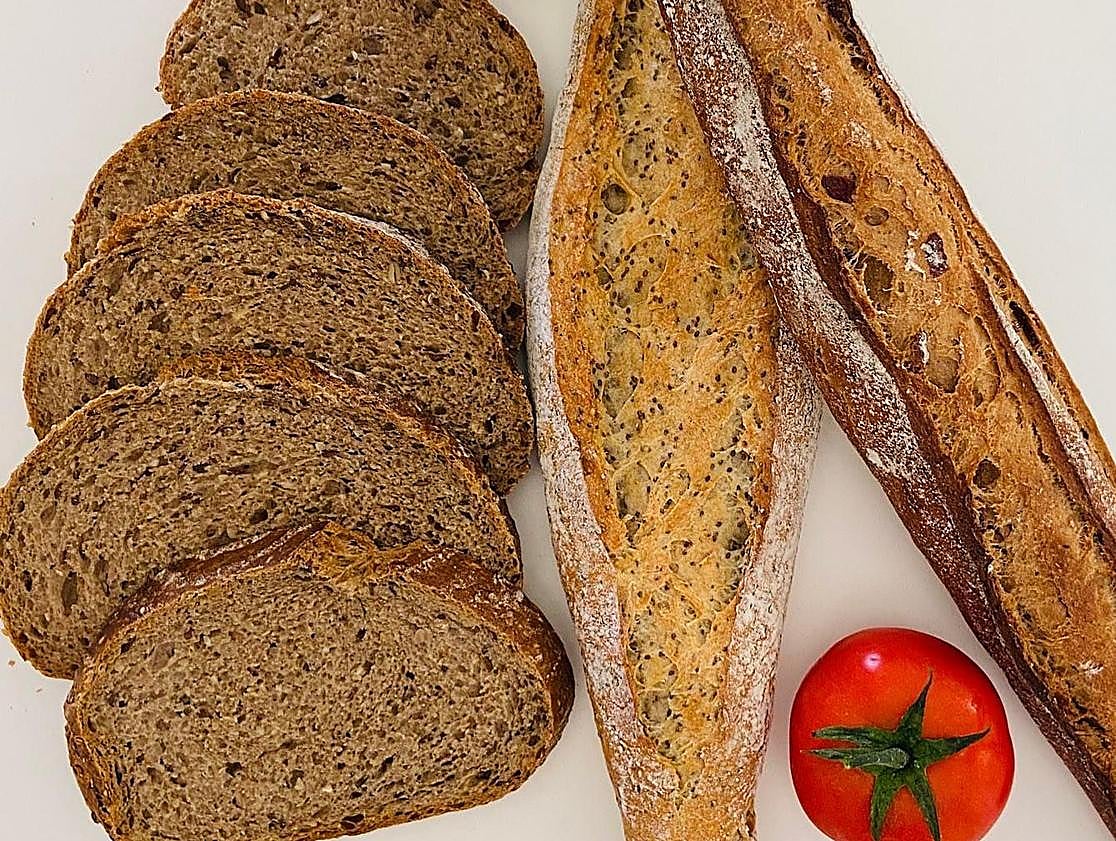 Imagen principal - Rebanadas de pan y barras de masa madre. Una de las empanadillas que elaboran en Pan Moreno. Hogaza de pan artesanal.