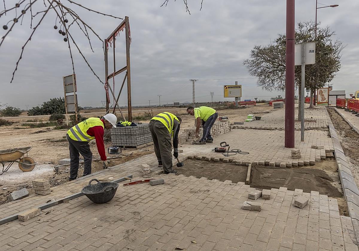 Unos obreros trabajan en las acometidas de la luz de la ZAL, cuyos terrenos están al fondo.
