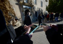 Adolescentes consultan su móvil a la salida de un instituto en Murcia.