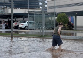 Una mujer cruza la avenida Miguel de Cervantes de Murcia, inundada de agua por unas lluvias en junio de este año.