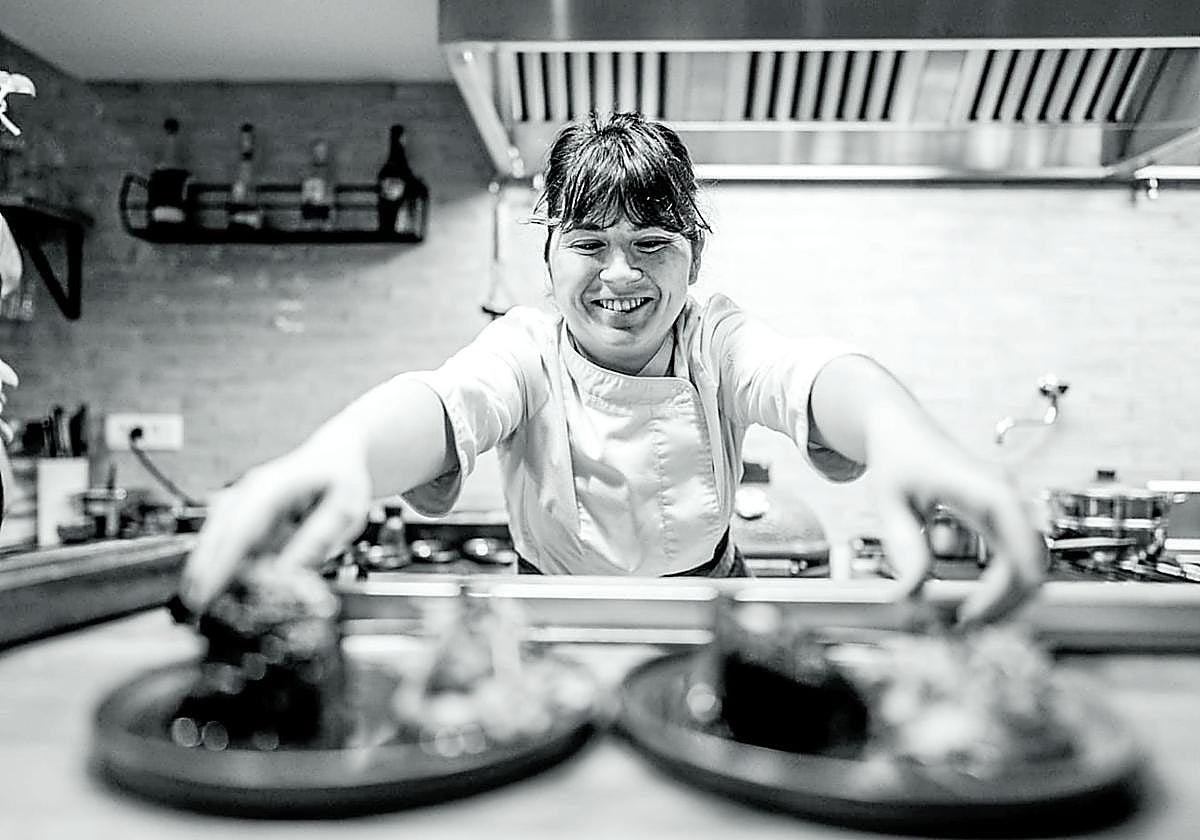 Pilar Olivares saca dos platos de la cocina del restaurante.