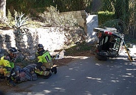 Bomberos atienden al herido tras sacarlo del coche donde había quedado atrapado.