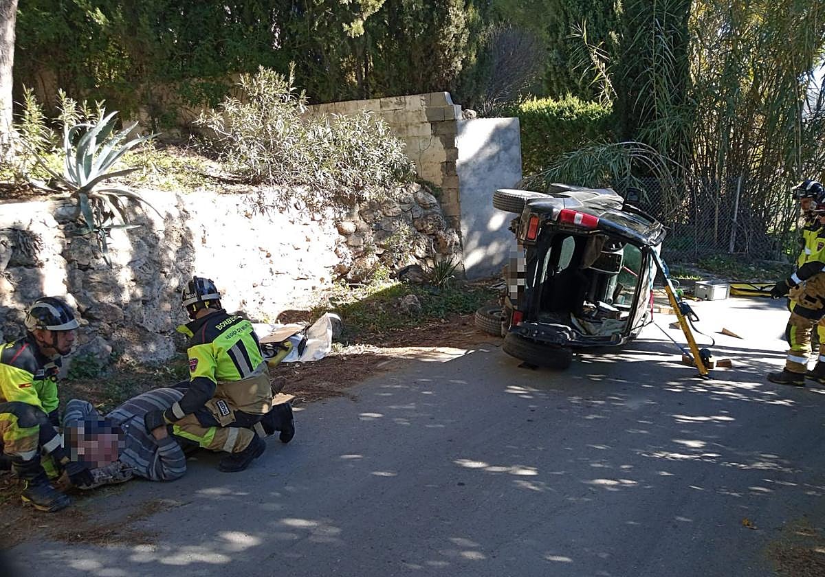Bomberos atienden al herido tras sacarlo del coche donde había quedado atrapado.