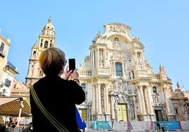 Una viandante fotografía la restaurada fachada de la Catedral de Murcia.