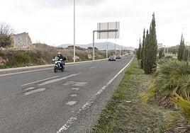 Una motocicleta circula por la Avenida Víctor Beltrí, junto a uno de los muchos tramos deteriorados que tiene esta carretera.