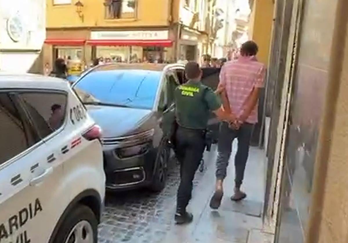 Un Guardia Civil lleva esposado al detenido.