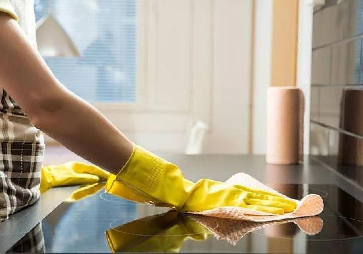 Una mujer limpia una cocina.