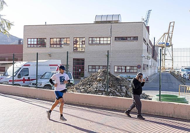 Dos personas pasan ante el edificio de oficinas y talleres.