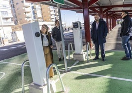 La alcaldesa, acompañada por Ortega y técnicos, mira un poste de recarga eléctrica del parking.