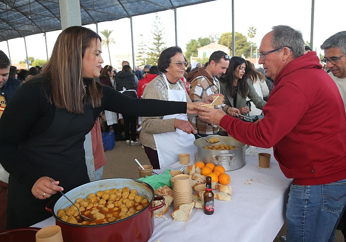 Unas vecinas reparten pelotas galileas a unos asistentes a la fiesta popular.
