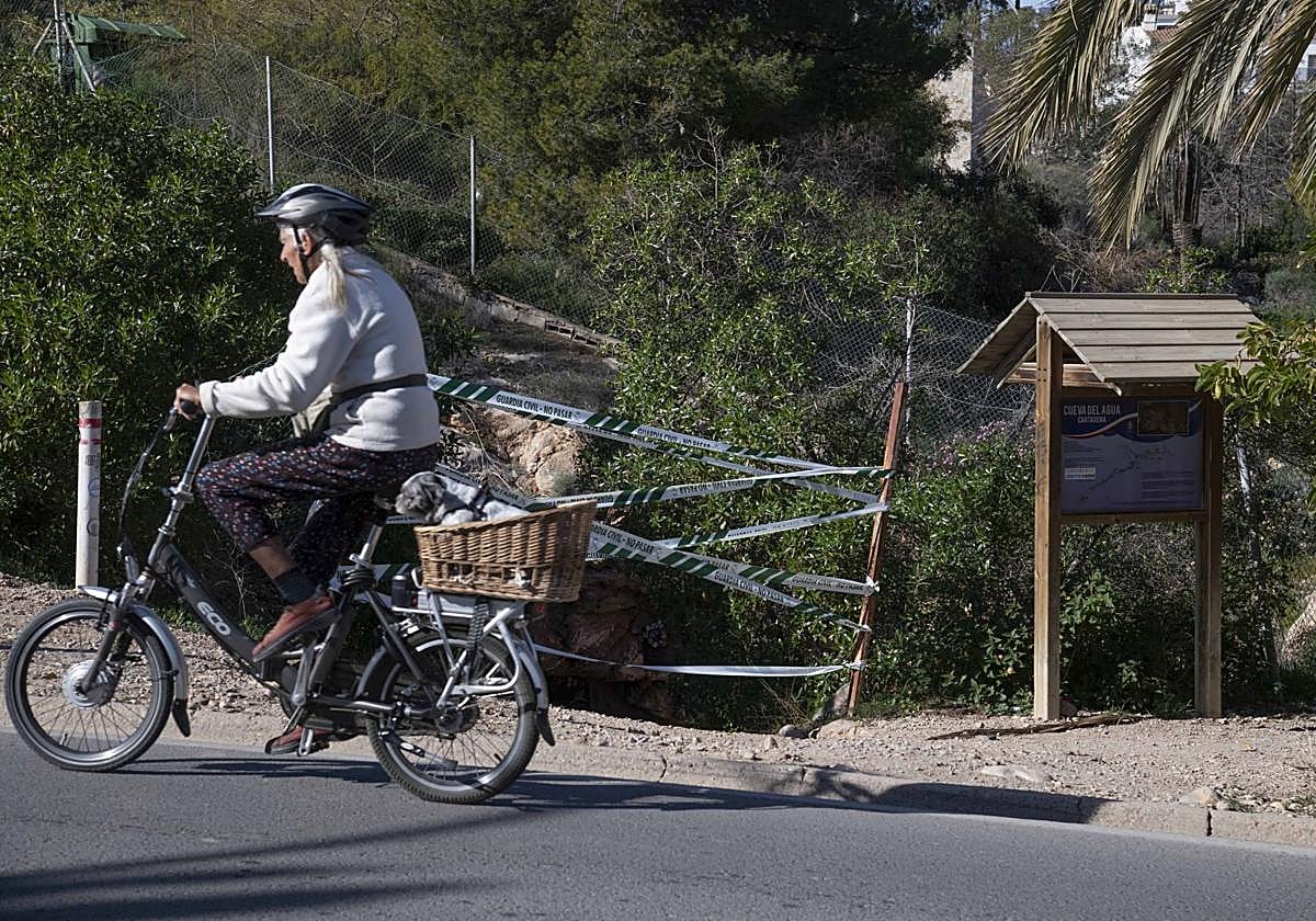 Una persona en bicicleta pasa frente a la entrada a la Cueva del Agua, en Isla Plana, este lunes.