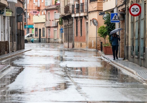 Un viandante camina con paraguas por una pedanía de Murcia, en una imagen de archivo.