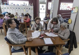 La directora del centro, Inmaculada Navarro, ayuda a una mujer a hacer una actividad, junto a otras mayores, en el salón del centro de día de la Hospitalidad Santa Teresa.