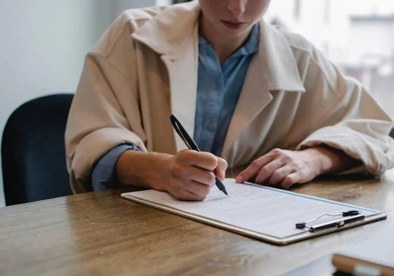 Una mujer rellena un formulario.