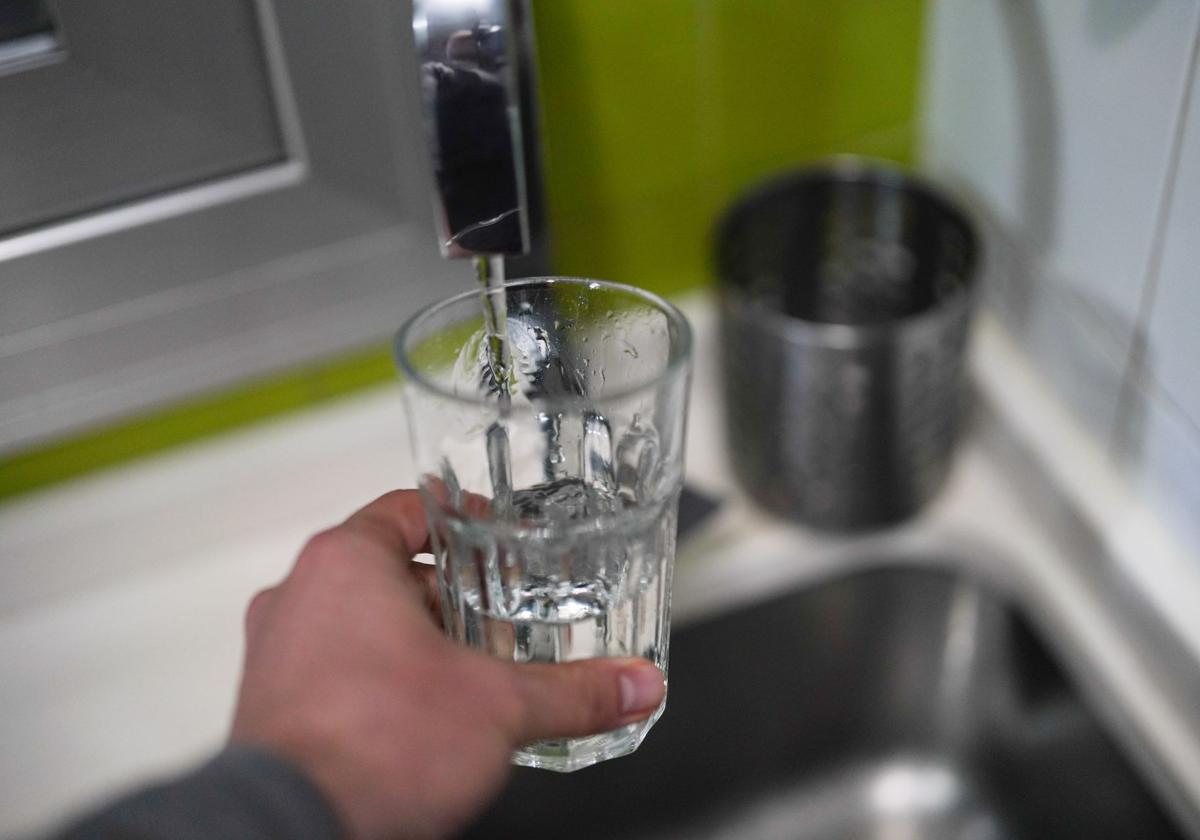 Un hombre llena un vaso con agua del grifo.