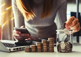 Una mujer mete una moneda en una hucha.