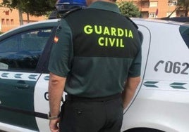 Un agente de la Guardia Civil junto a su vehículo.