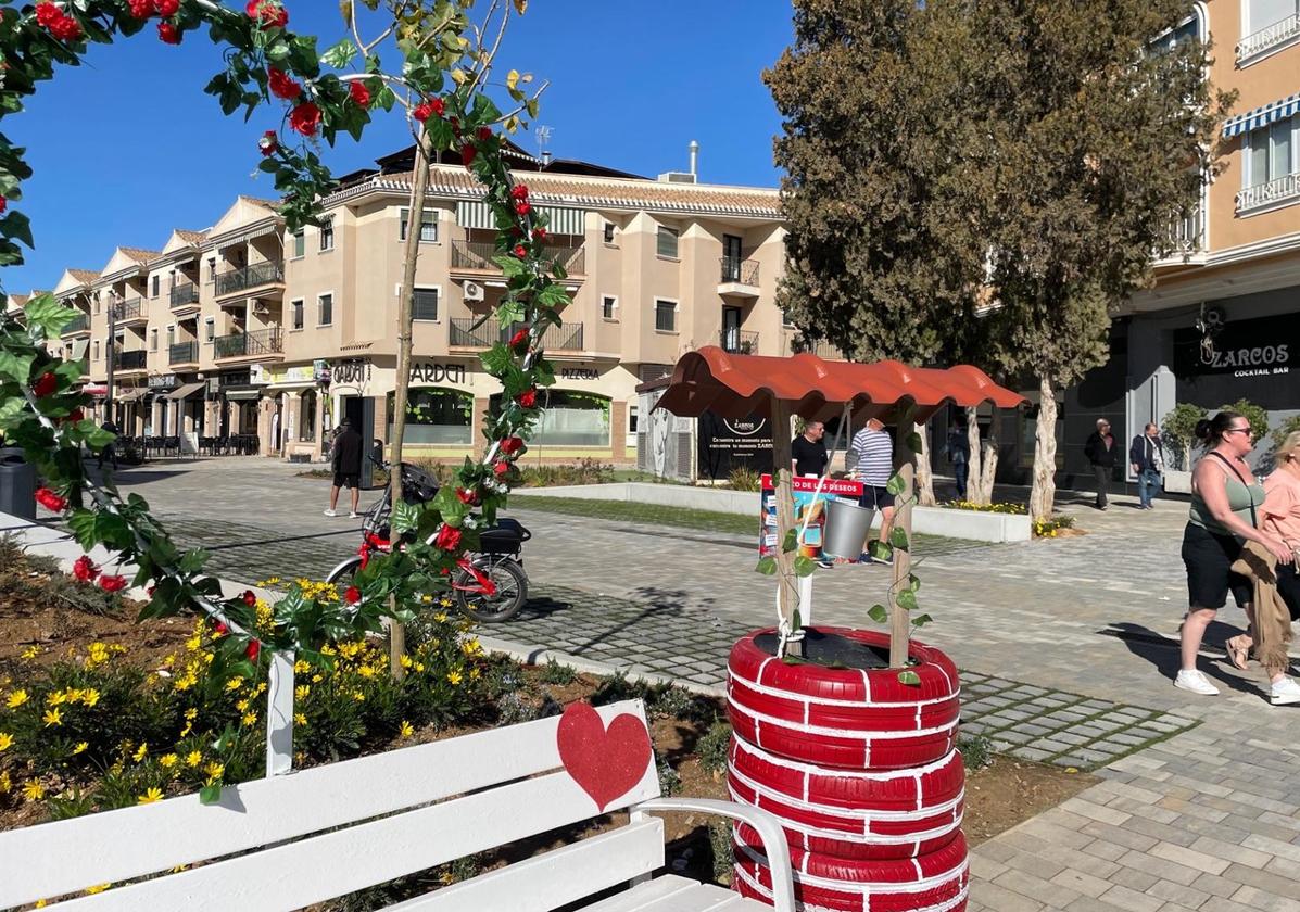 Turistas pasean ante la decoración de San Valentín en la avenida Río Nalón de Los Narejos.