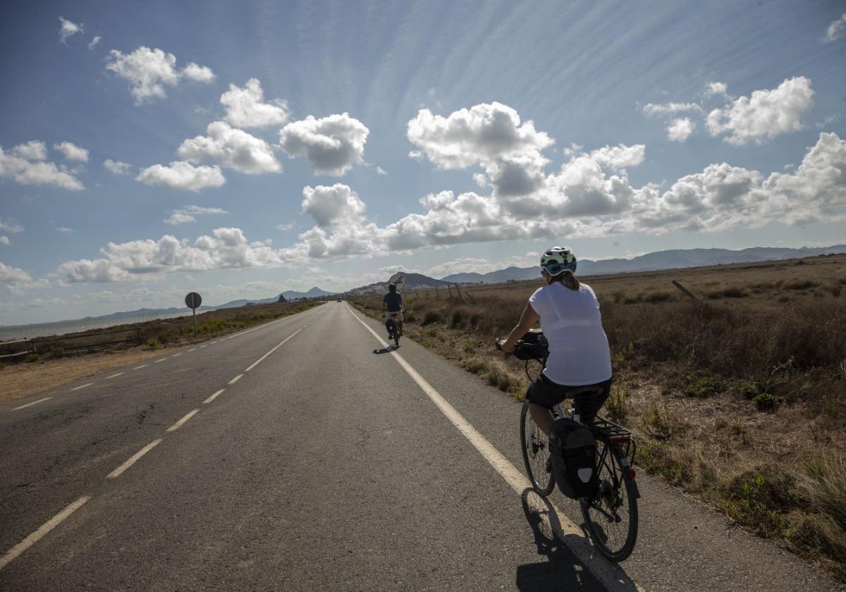 Una pareja pasea en bici por la carretera que une El Carmolí y Los Alcázares a través de la ribera del Mar Menor, en una imagen de archivo.