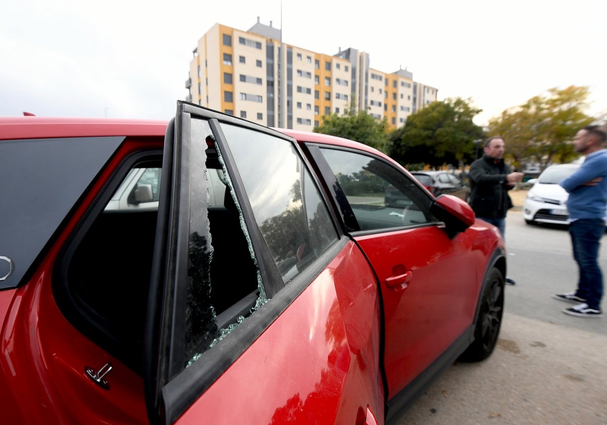 Dos vecinos hablan junto a uno de los vehículos vandalizado el pasado fin de semana junto al residencial Parque Norte de la pedanía murciana de Cabezo de Torres.