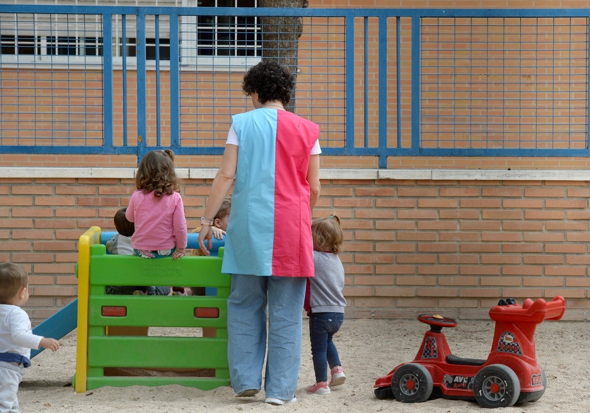 Varios niños con una de su educadora en una escuela infantil.