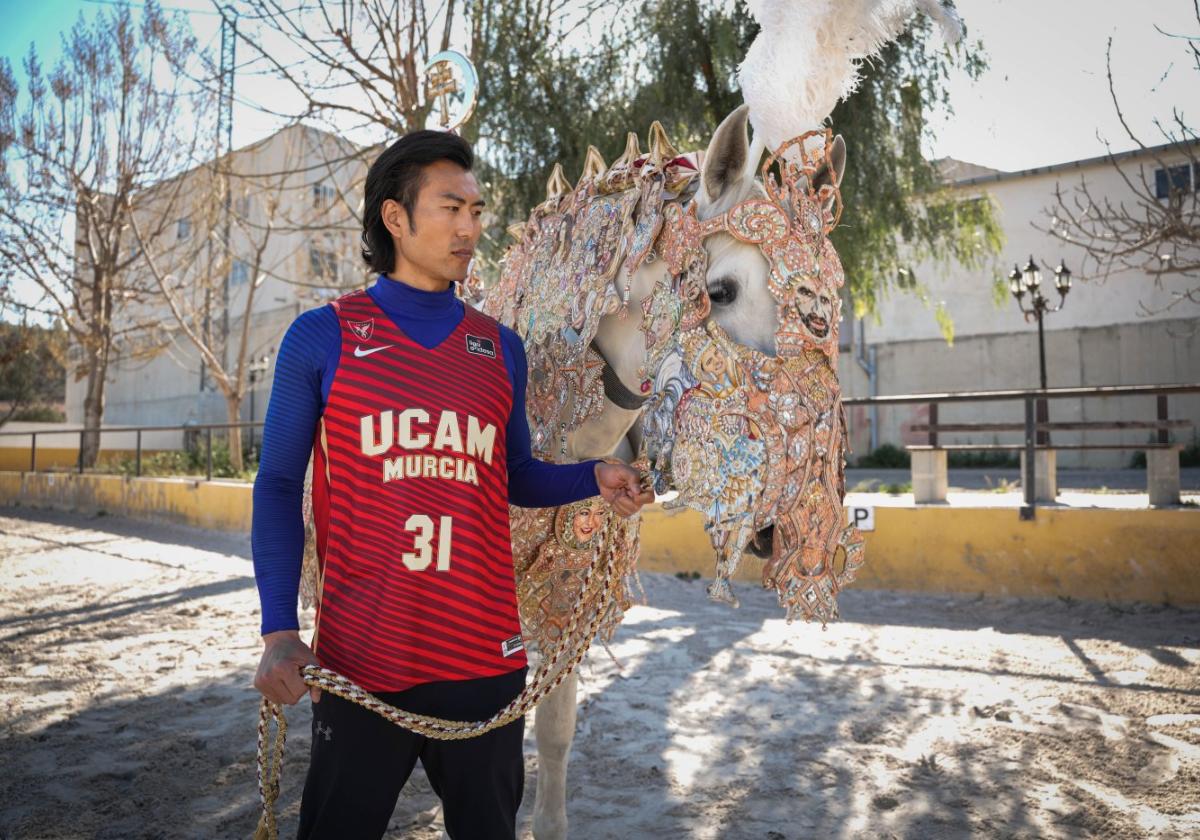 Un modelo posa con la nueva equipación y un caballo de los empleados en la fiesta caravaqueña.