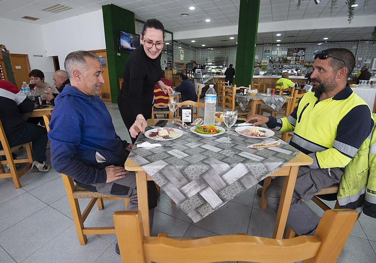 Una camarera del restaurante Las Palmeras IV, en el Polígono Industrial Oeste, sirve el menú del día a dos clientes.