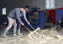 Trabajadores de una empresa de la carretera de Caravaca retiran el barro que anegó el local.