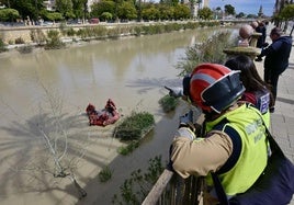 Un bombero señala un punto a sus compañeros en una zódiac, en el dispositivo de búsqueda coordinado por la Policía Nacional.