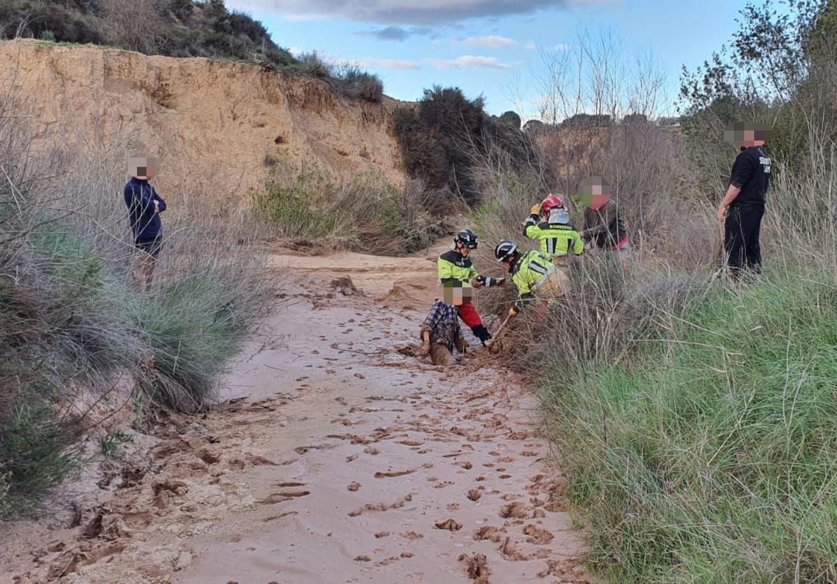 Los bomberos ayudan al hombre a salir del barro.