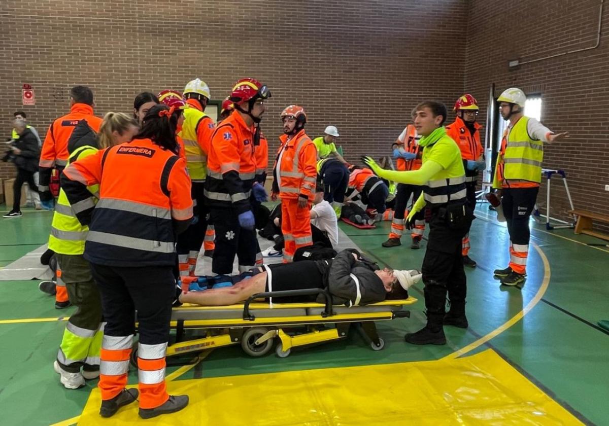 Sanitarios de emergencias preparan para su traslado al hospital a varios de los heridos en el gimnasio del instituto, durante el simulacro.