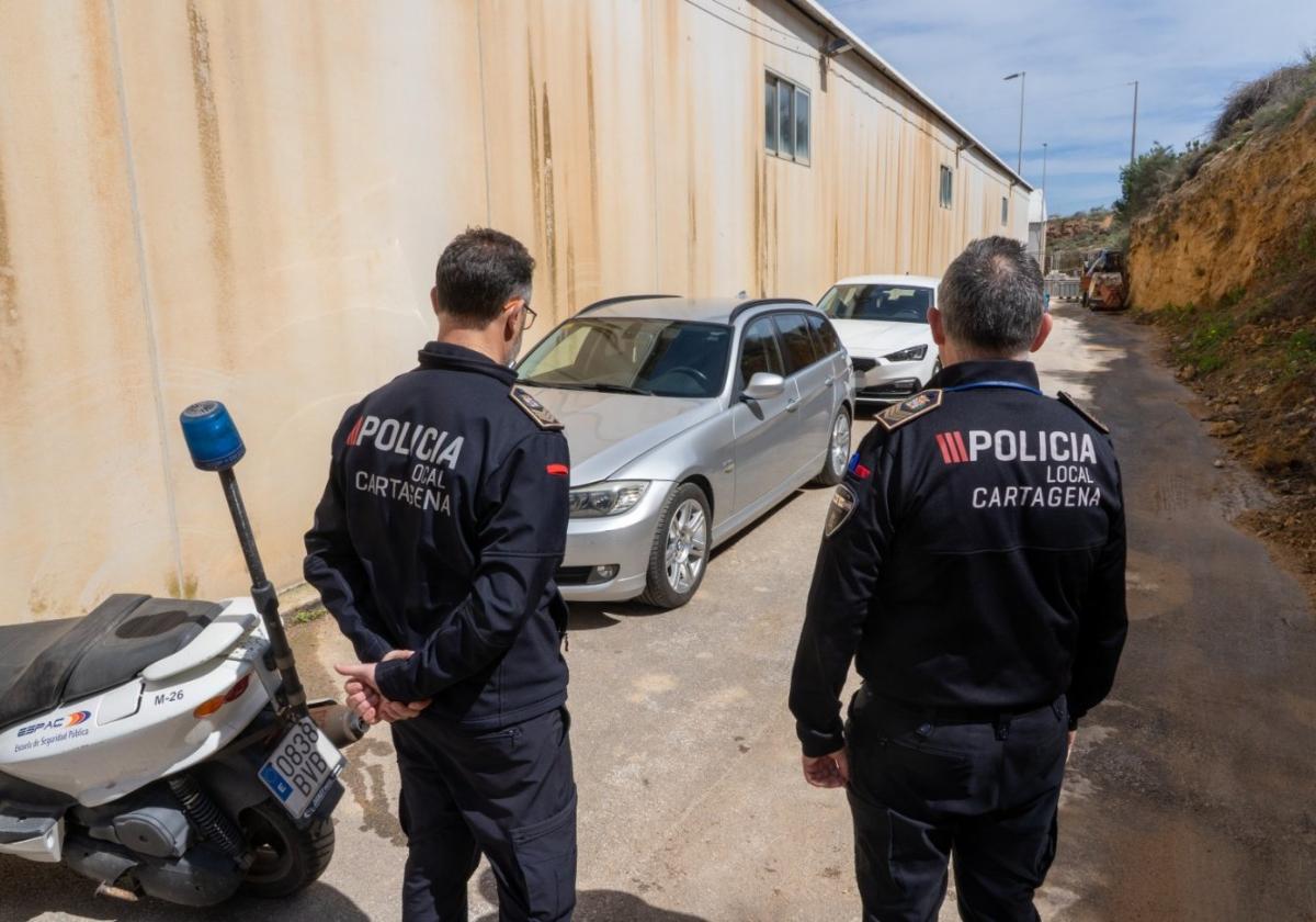 Dos agentes de la Policía Local, en el depósito municipal, junto a dos vehículos abandonados que fueron retirados de la calle.