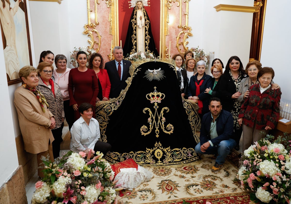 Miembros del Paso Encarnado rodean el nuevo manto de la Virgen de la Soledad.