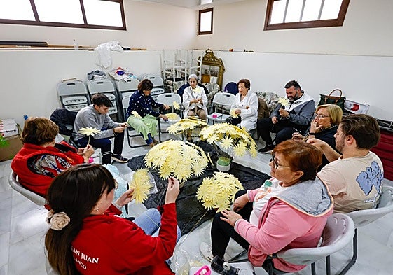 Cofrades del Paso Blanco preparan las flores de palma para el trono de San Juan Evangelista.